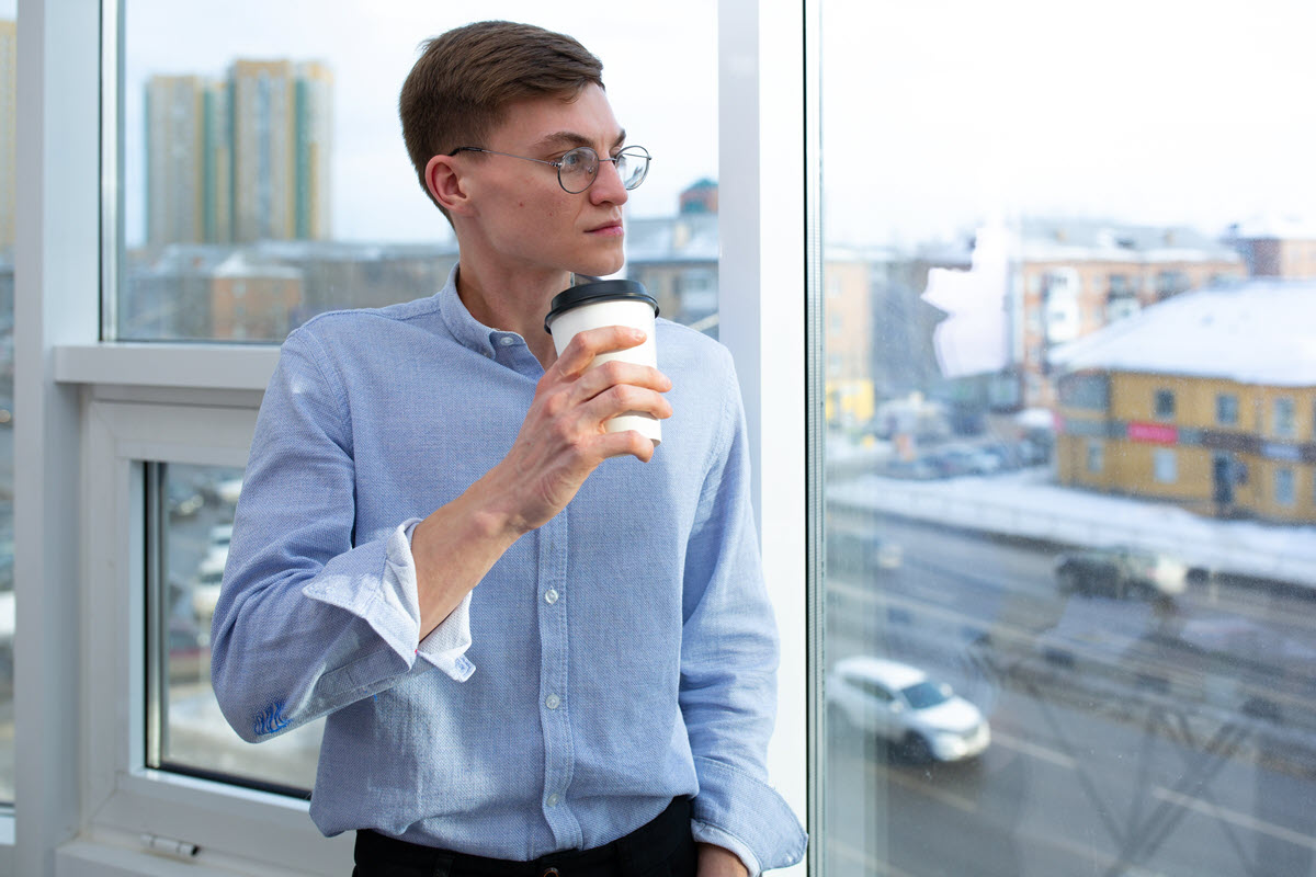 Photo by Mikhail Nilov - Man drinking coffee looking out window